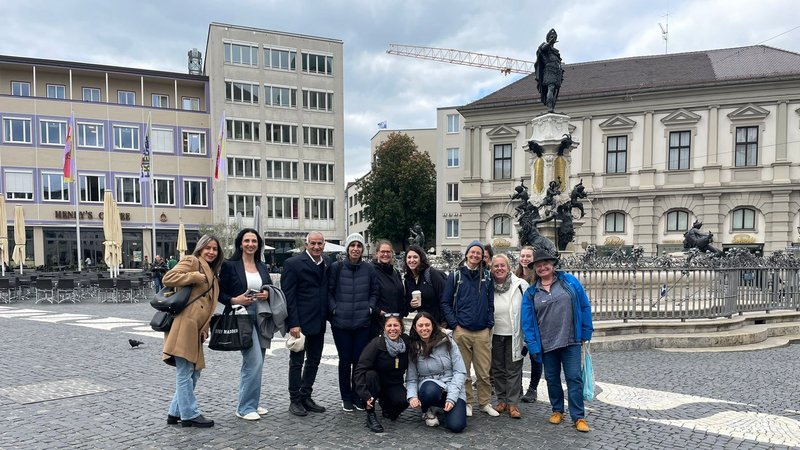 Gruppenbild von ca. 12 Personen vor dem Augusta Brunnen in Augsburg