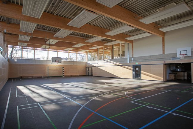 Blick in die lichtdurchflutete Turnhalle mit Geräteraum