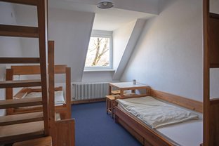 Blick in einen Übernachtungsraum mit zwei Betten und einer Sitzgruppe